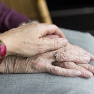 caregiver holding the hand of an elderly woman