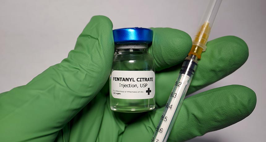 green gloved hand holding fentanyl and needle