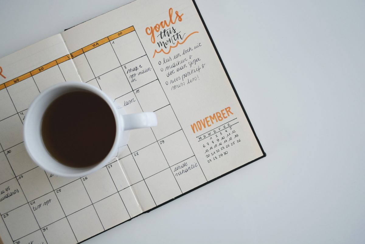 white ceramic mug with coffee on a planner