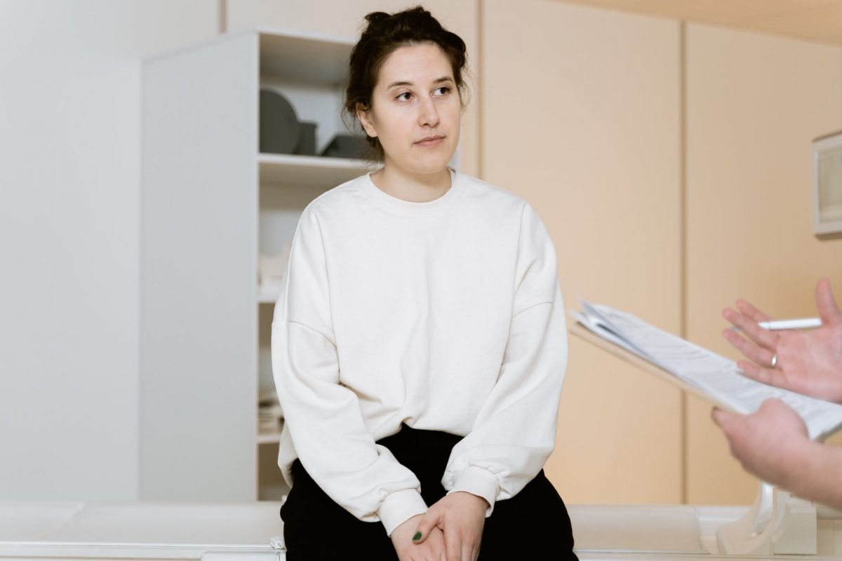 younger lady with white sweater sitting on a doctor table