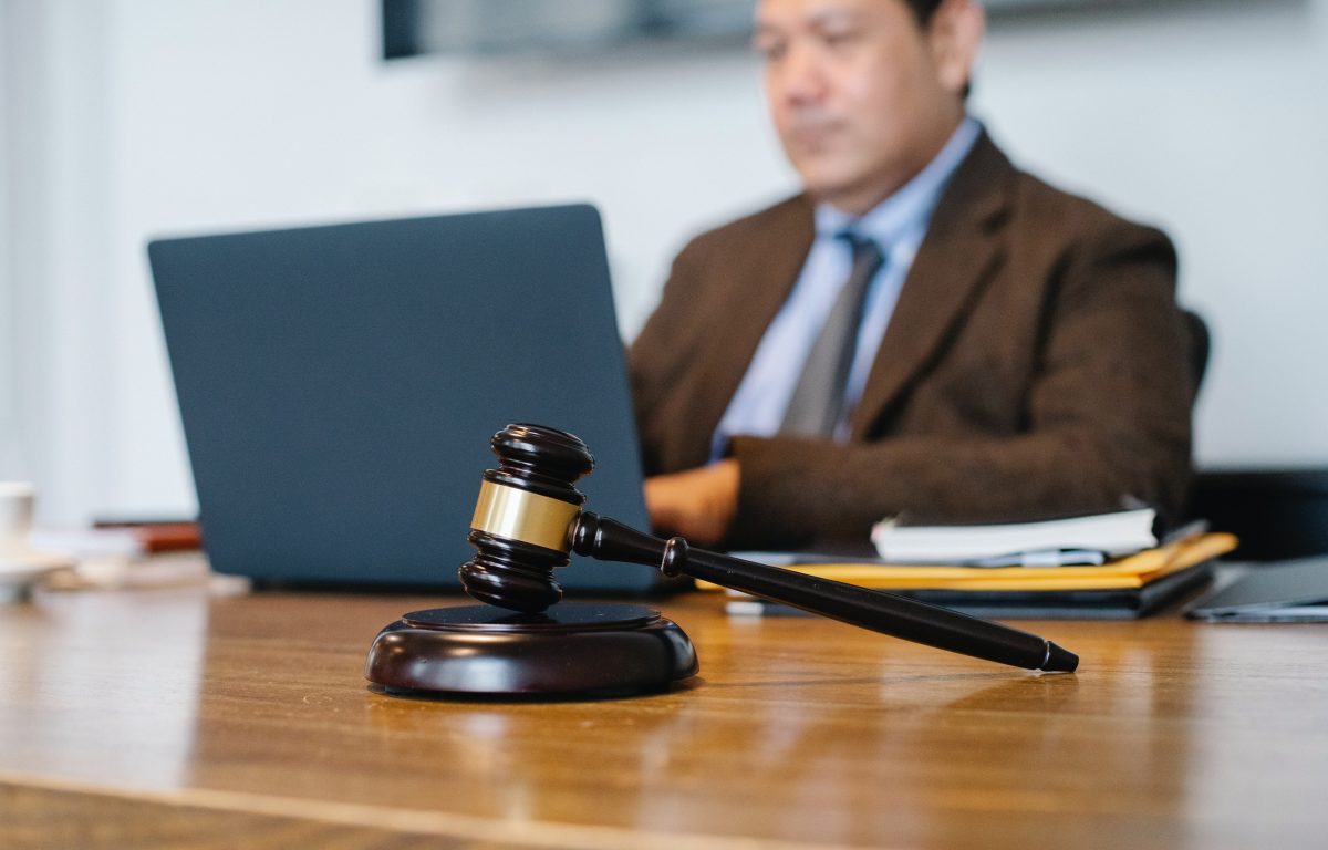 Asian judge working on laptop with gavel on table