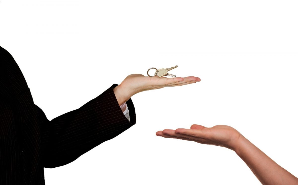 Real estate agent hands over keys to home with white background