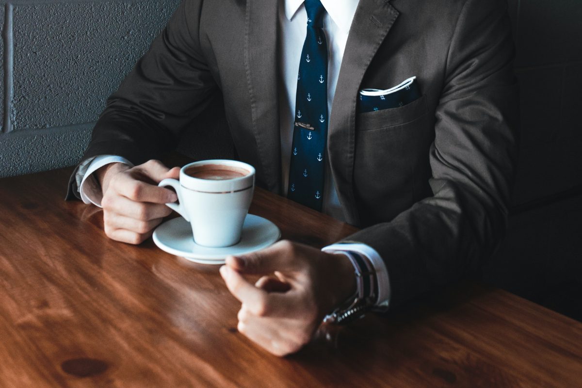 business man holding cup filled with coffee