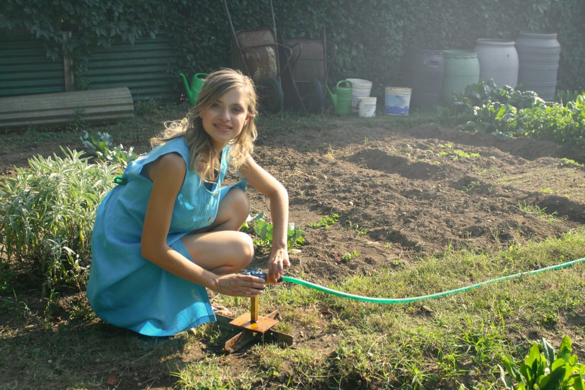 girl in the garden connect water hose to sprinkler