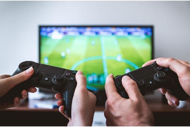 2 playstation controllers with football on tv