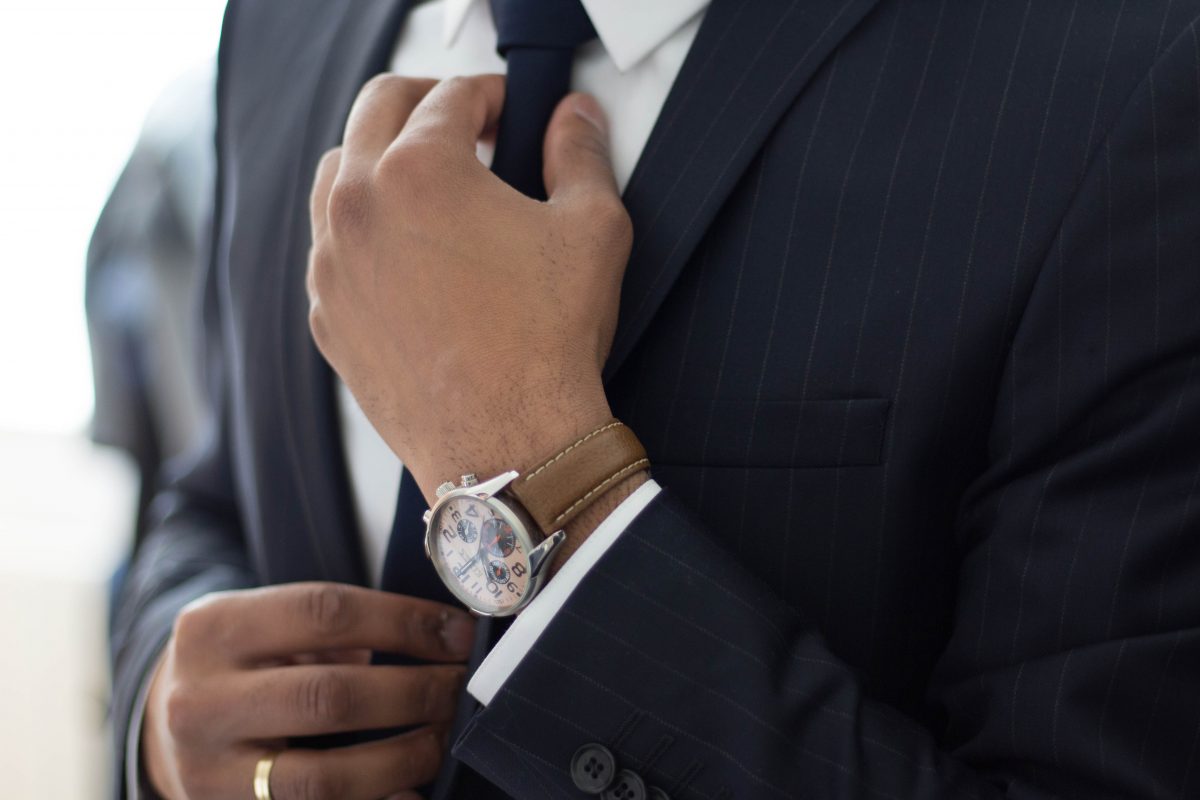 business man wearing a watch and suit fixing his tie