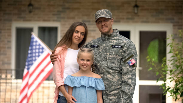 military man with wife and daughter standing in front of house