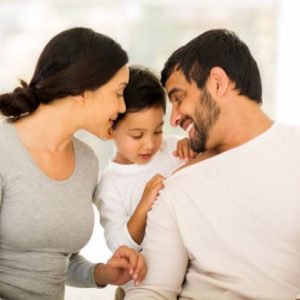 mom, dad, and son sitting together on a bed