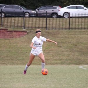 Emma Young kicking soccer ball at Mississippi college
