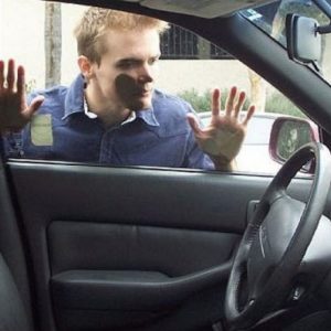 man with face against window looking into a locked car