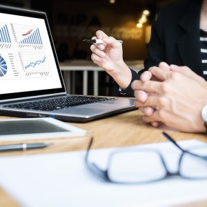 professional going over graphs at the table with a client. glasses laying on paper.