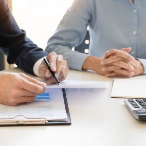 professionals sitting at table with calculator and pen in hand