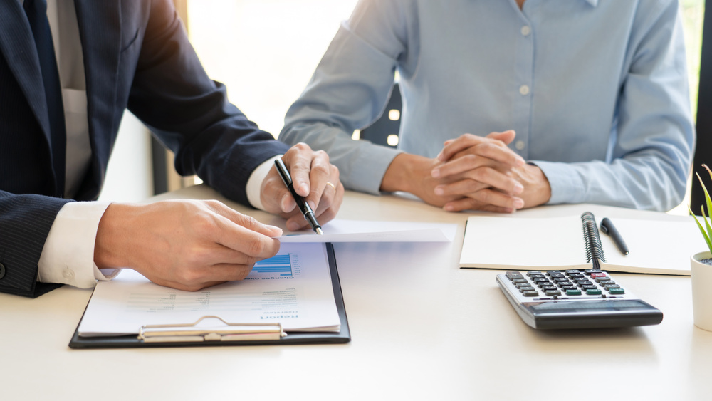 professionals sitting at table with calculator and pen in hand