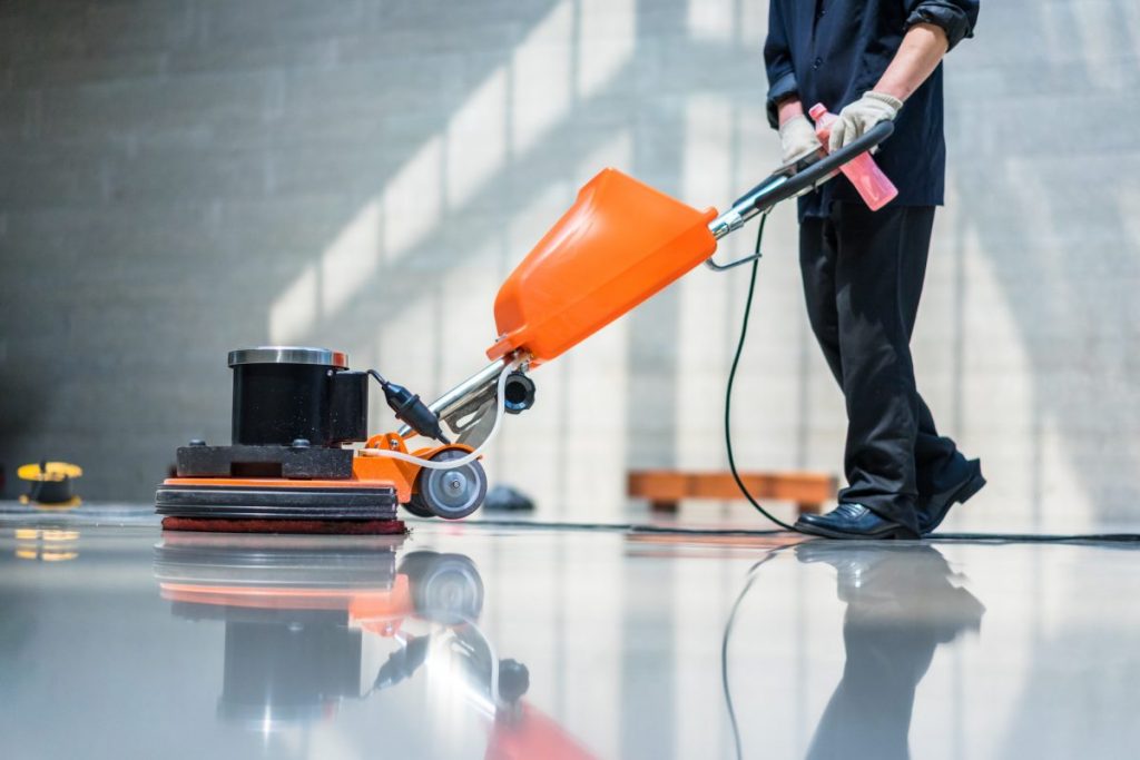 janitor cleaning floors with wax machine