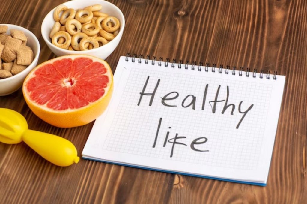 healthy life written on paper with grapefruit and other healthy snacks on the table