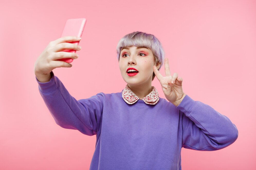 Girl in purple sweater throwing peace sign and doing a selfie