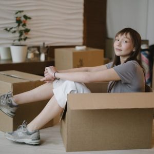 A girl sitting inside of a cardboard box