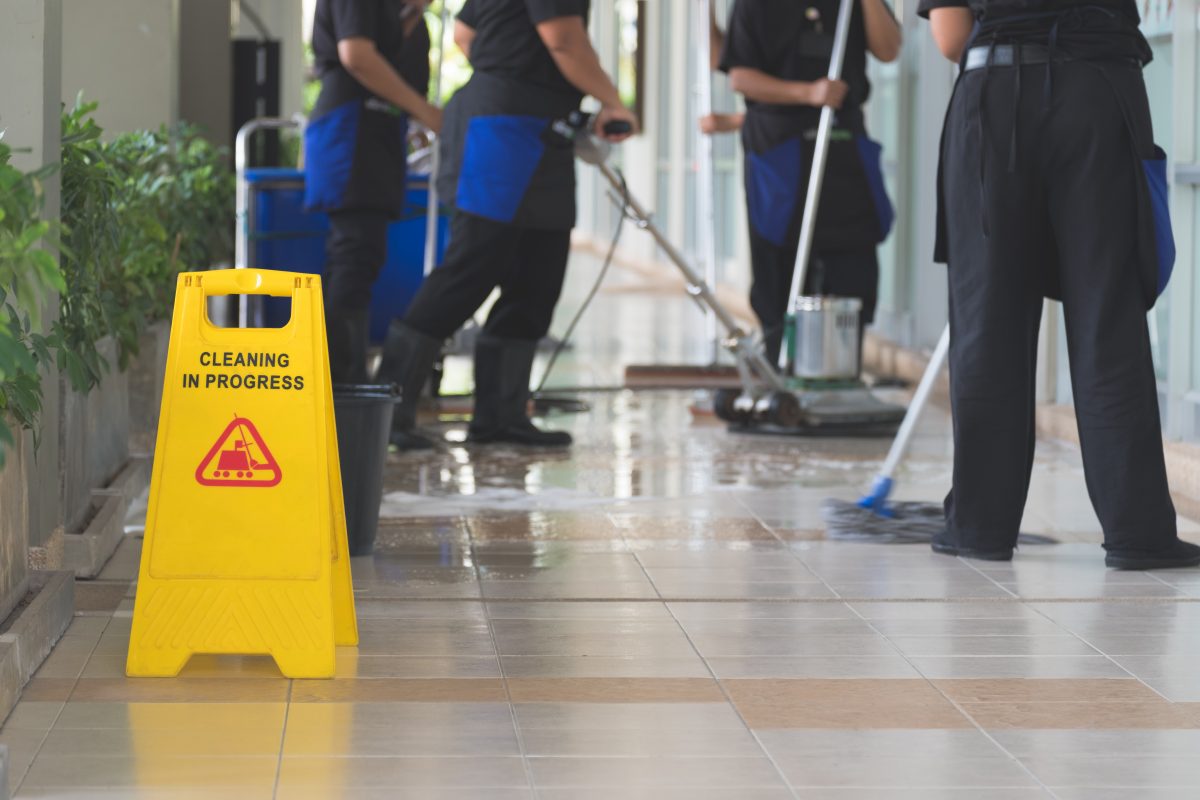 cleaning crew mopping the floor with a sign that says cleaning in progress