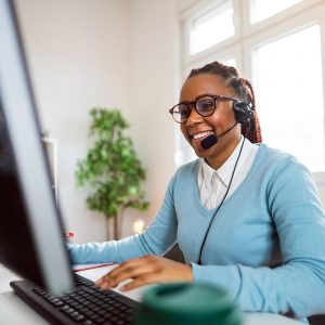 african american female with headphones sitting in front of a computer at a call center