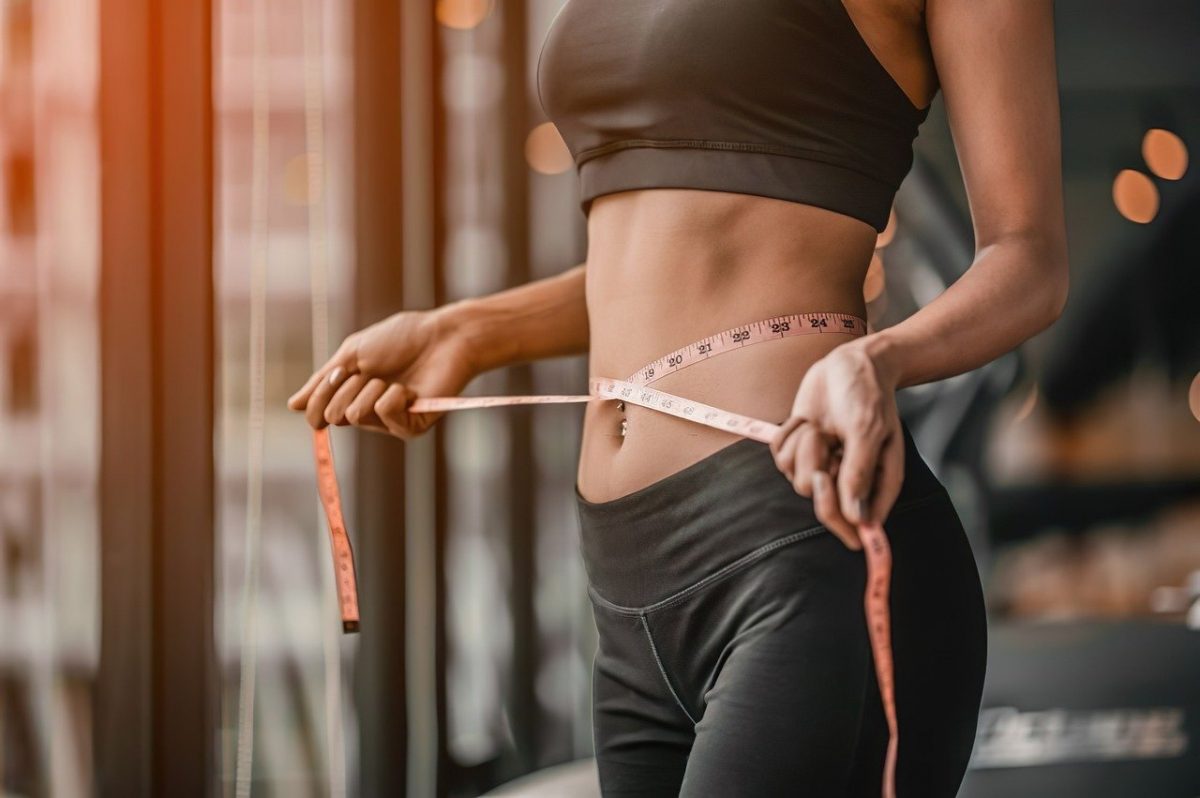 skinny woman showing midsection with measuring tape around her stomach