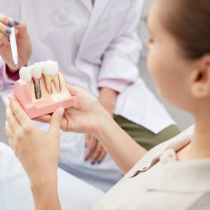 woman holding model teeth with dentist pointing at the tooth