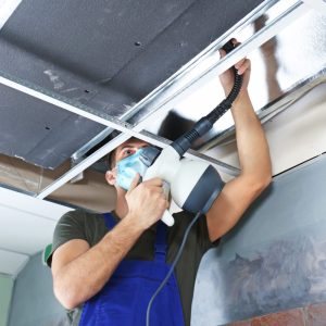 air duct cleaning professional with mask on ladder