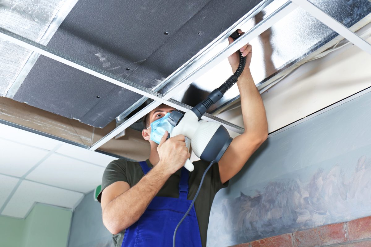 air duct cleaning professional with mask on ladder