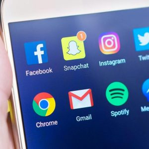 person holding iphone with social media icons on the screen