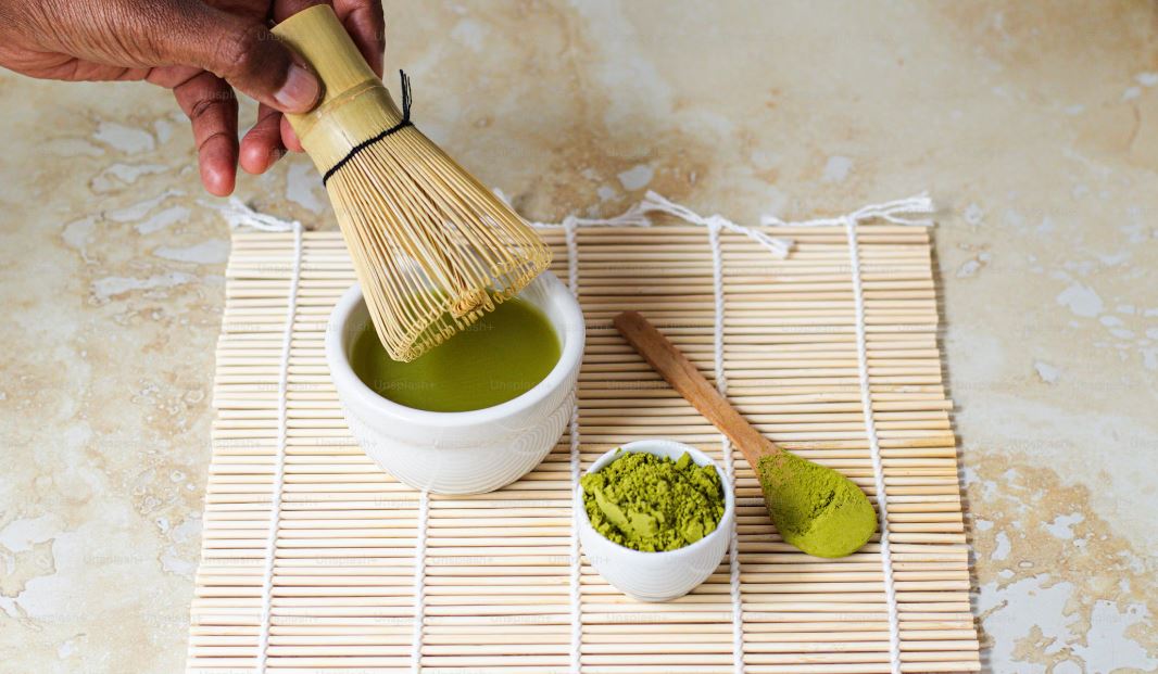 a person holding a wooden brush over green powder