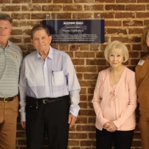 Jannelle Landrum Hamilton, second from right, and her husband, Dr. Joseph H. Hamilton Jr., second from left, pose with a plaque acknowledging Monroe J. Landrum Sr.'s contributions to the construction of Alumni Hall. The couple was treated to a tour of the building by Jim Turcotte, left, and Katrina Pace.