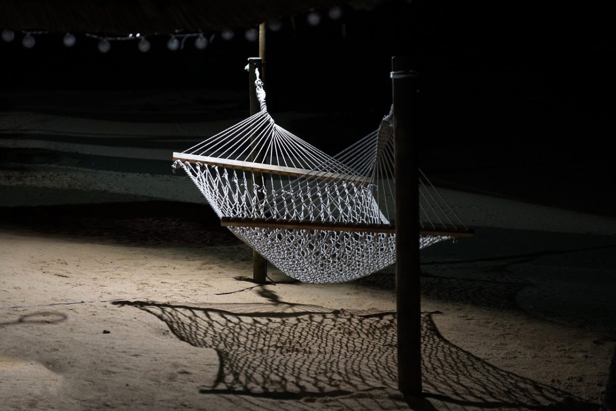 empty white hammock set up on the beach at night