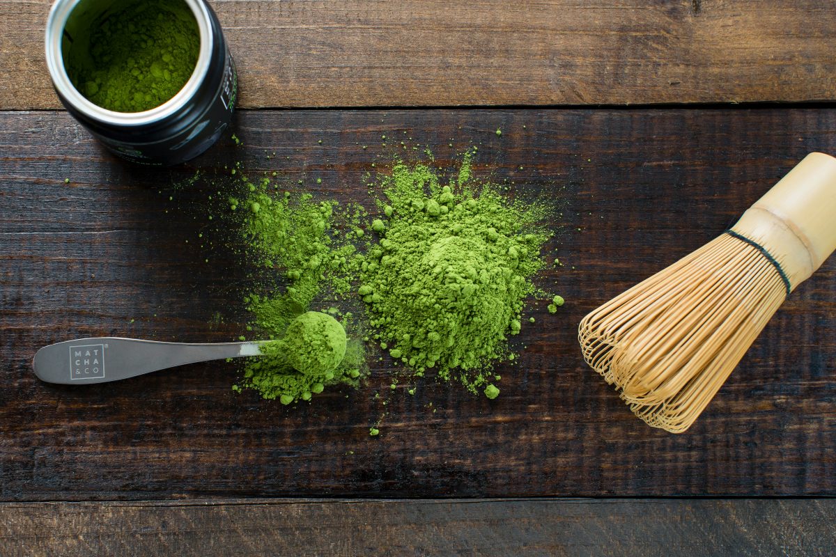 matcha co green powder in a spool sitting on wooden table