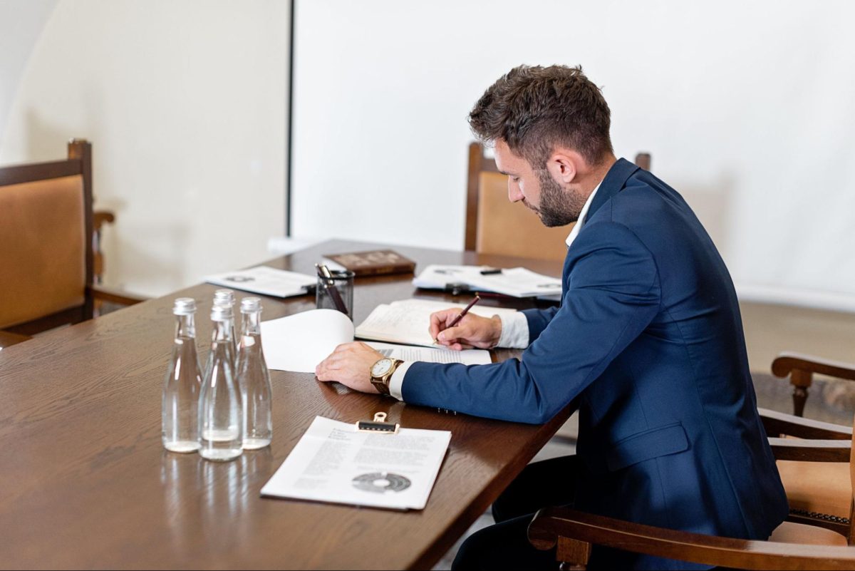 professional man sitting at conference table with pen in hand signing papers