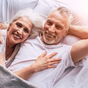 elderly couple cuddle in the bed together