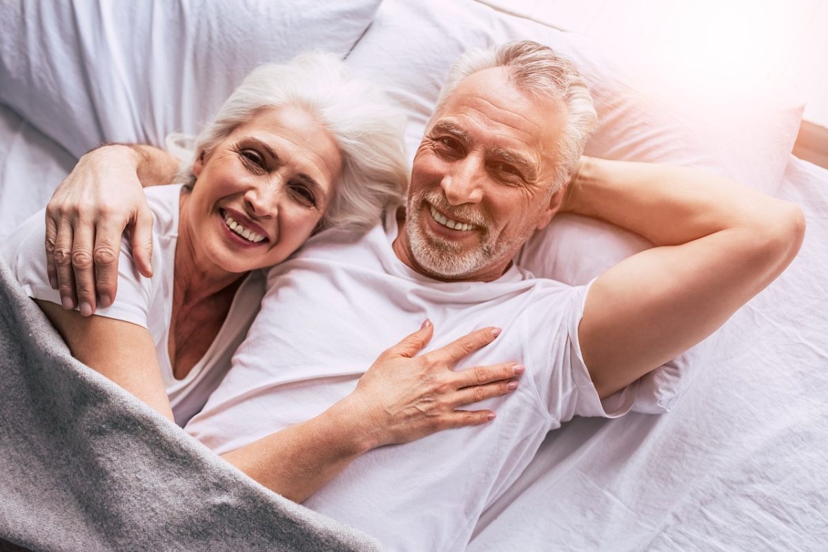 elderly couple cuddle in the bed together