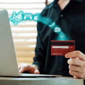 Customer Holding Credit Card with Hologram Icons Coming Out of a Laptop  