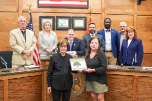 Pictured at a recent Board of Alderman meeting, MUFC Executive Director Donna Yowell presents a certificate to Clinton Visitor Center Director Marsha Barham recognizing that the Visitor Center has achieved arboretum certification, one of three in the city. The other two are the Quisenberry Library and the neighborhood of Bruenburg.