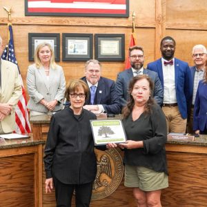 Pictured at a recent Board of Alderman meeting, MUFC Executive Director Donna Yowell presents a certificate to Clinton Visitor Center Director Marsha Barham recognizing that the Visitor Center has achieved arboretum certification, one of three in the city. The other two are the Quisenberry Library and the neighborhood of Bruenburg.
