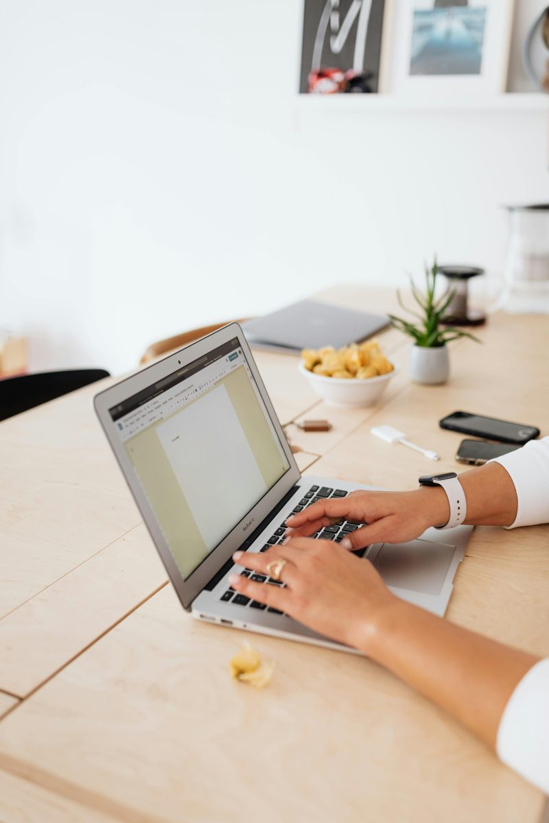 woman tping on a laptop sitting on a table