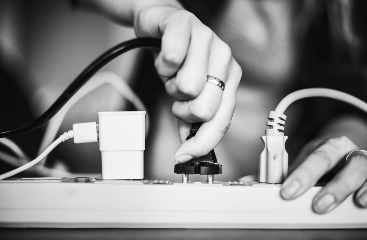 black and white photo of woman plugging in cord to the power strip