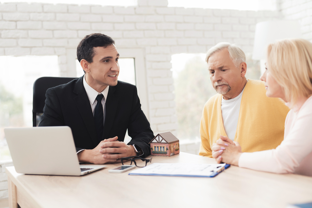 older couple sits with business man in suit with laptop