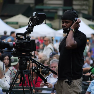african american male with headphones on working a camera at a crowded event