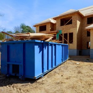 contracting dumpster sitting in front of a home being built with wood inside