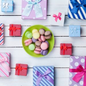 brightly colored gift boxes on a wooden table with a plate of macaroons
