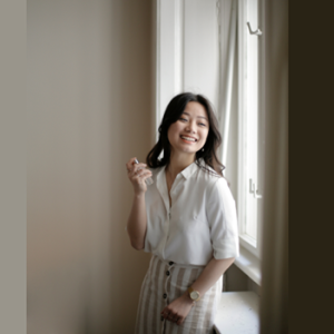 woman standing and smiling in front of a window