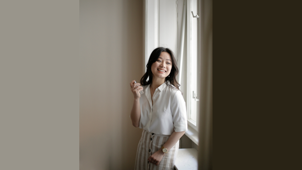 woman standing and smiling in front of a window