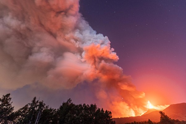 smoke filled sky with fire burning across the mountains