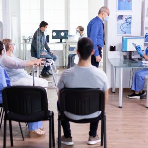 disabled senior woman with walking frame sitting in hospital waiting area