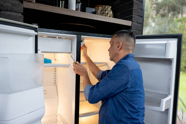 handyman fixes a refrigerator
