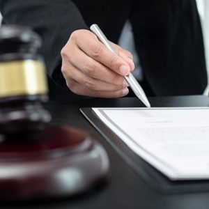 lawyer with pen in hand and gavel on table